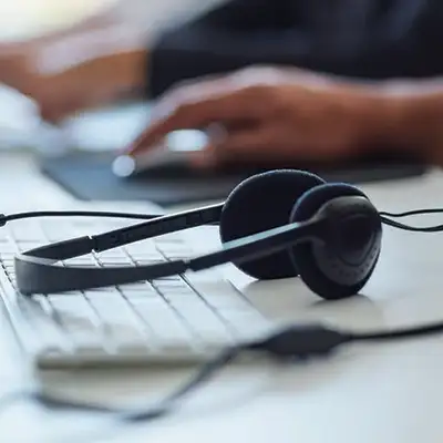 Person using mouse with headphones sitting on keyboard Person using mouse with headphones sitting on keyboard